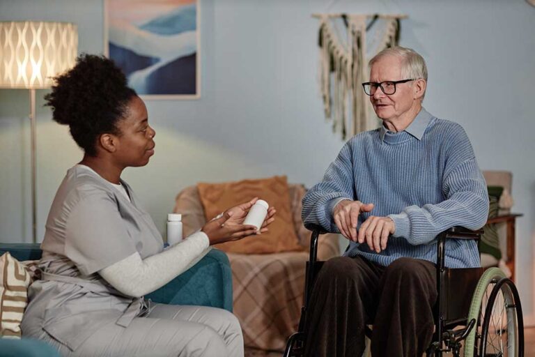 Older adult and family member reviewing admission forms, a medication list, and legal documents at a kitchen table.